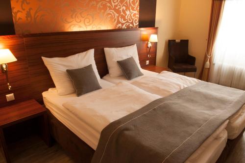 - une chambre dotée d'un grand lit avec des draps et des oreillers blancs dans l'établissement Hotel Restaurant Nassauer Löwen, à Nassau