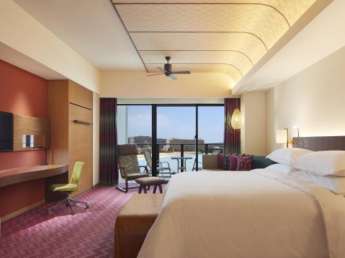 a hotel room with a large bed and a balcony at Sheraton Okinawa Sunmarina Resort in Onna