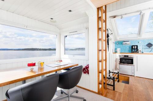 Beach house in Oslo في أوسلو: مطبخ وغرفة طعام في قارب مع طاولة وكراسي