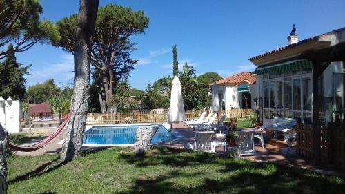 a swimming pool with a hammock and a house at Xanadu Rural in Chiclana de la Frontera