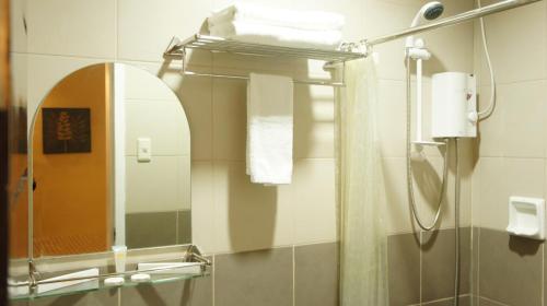 ein Bad mit einer Dusche und einem Spiegel in der Unterkunft Urbantel Hotel in Lucena