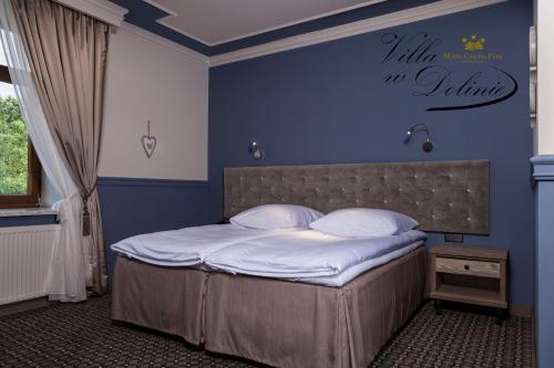 een slaapkamer met een bed met een blauwe muur bij Apartamenty Willa w Dolinie in Tarnów