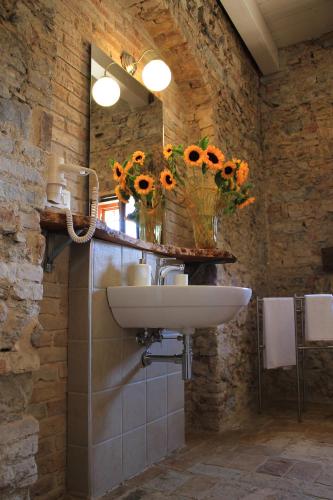 a bathroom with a sink and a vase of sunflowers at La Peschiera B&B in San Lorenzo del Vallo