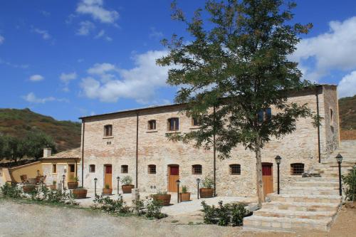 un vieux bâtiment en pierre avec un arbre en face de lui dans l'établissement La Peschiera B&B, à San Lorenzo del Vallo
