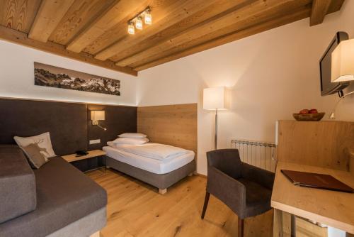 a bedroom with a bed and a couch and a desk at Hotel Unterwirt in Reit im Winkl