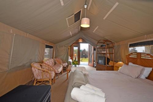 a room with a bed and a couch in a tent at Hoopoe Haven Guest House in Chartwell
