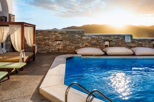 a swimming pool in a hotel with the sun setting at Ios Resort in Ios Chora