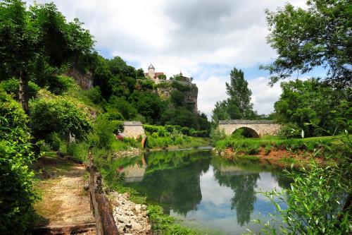 a river with a bridge and a castle on a hill at Le Pont de L'Ouysse in Lacave