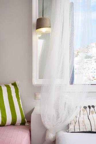 a window with a white curtain and a couch at Ios Resort in Ios Chora