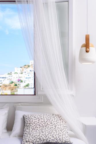 a bedroom with a window with white curtains at Ios Resort in Ios Chora