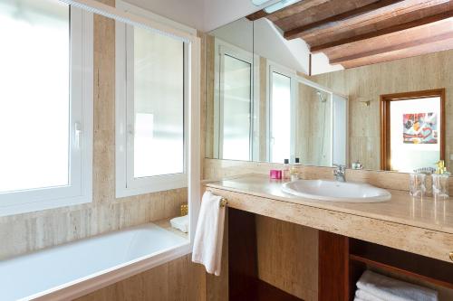 a bathroom with a sink and a mirror and a tub at Casa Cosi Mallorca I in Barcelona