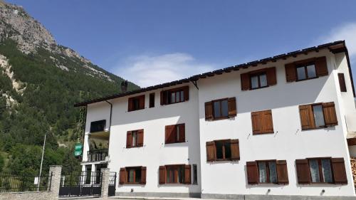 a white building with wooden windows and a mountain at Hotel Roburent in Argentera