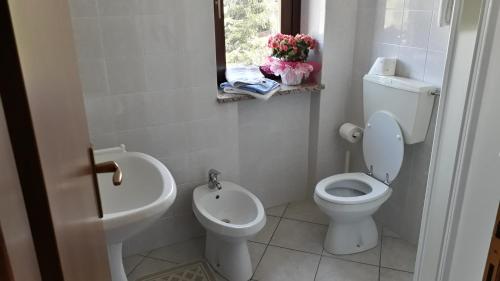 a white bathroom with a toilet and a sink at Hotel Roburent in Argentera