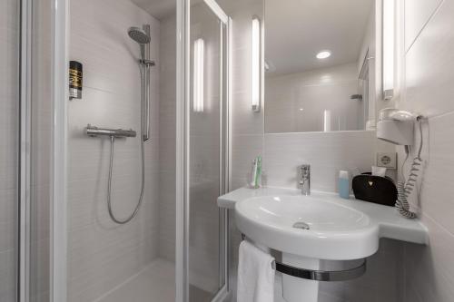 a white bathroom with a shower and a sink at Serways Hotel Heiligenroth in Montabaur