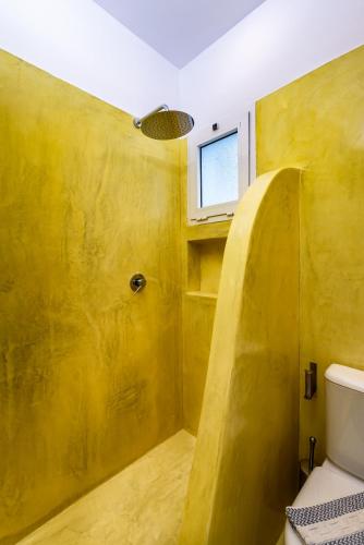 a yellow bathroom with a toilet and a window at Ios Resort in Ios Chora