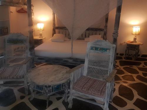a bedroom with a bed and two chairs and tables at Scorpio Villas Resort in Malindi