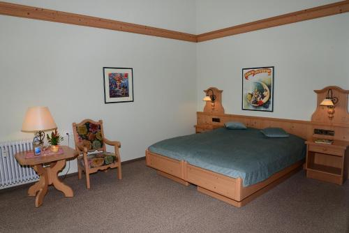 a bedroom with a bed and a table and a chair at Residence am Weinberg / Travellers Hotelbetriebs GmbH in Sasbachwalden