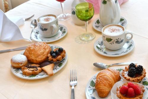 a table with plates of pastries and cups of coffee at Hotel La Sacca in Stresa