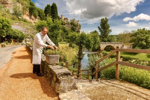 a man standing on a stone wall next to a bridge at Le Pont de L'Ouysse in Lacave