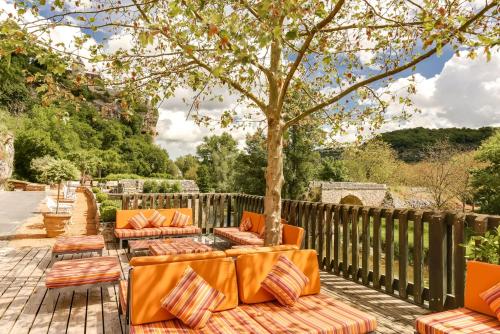 an outdoor patio with orange couches and a tree at Le Pont de L'Ouysse in Lacave