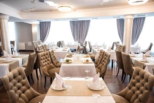 ein Restaurant mit weißen Tischen und Stühlen und Fenstern in der Unterkunft Shato Hotel ШАТО in Chervonograd