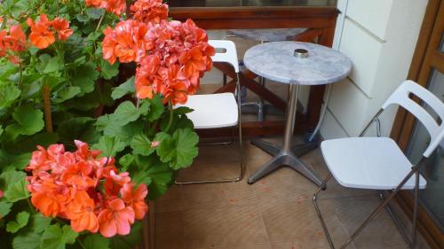 a table and two white chairs and orange flowers at Vila Silvia in Sovata