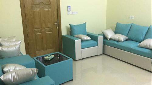 a living room with blue couches and a door at Rafeef Al Shamal رفيف الشمال شقق مخدومه - الحائط in Al Ḩāyiţ