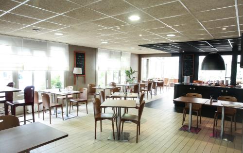 une salle à manger avec tables, chaises et fenêtres dans l'établissement Hôtel Inn Design Resto Novo Nantes Sainte Luce, à Sainte-Luce-sur-Loire