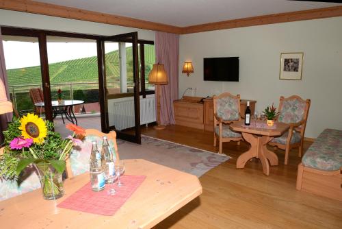a living room with a table and chairs and a television at Residence am Weinberg / Travellers Hotelbetriebs GmbH in Sasbachwalden