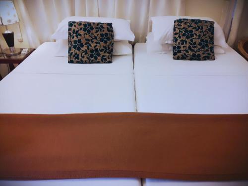 two beds in a room with white sheets and black pillows at Heavenly Homestay in Cochin