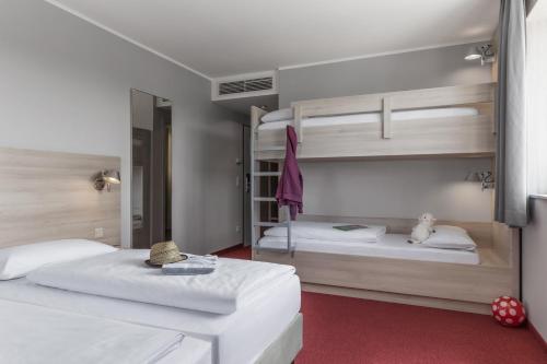 two beds in a room with two bunk beds at Serways Hotel Feucht Ost in Feucht