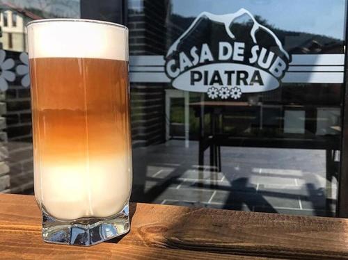 a glass of beer sitting on top of a table at Casa De Sub Piatra in Baia de Fier