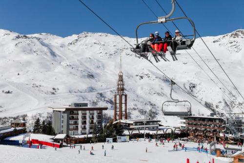 a group of people riding a ski lift in the snow at Résidence Odalys Chanteneige Croisette in Les Menuires