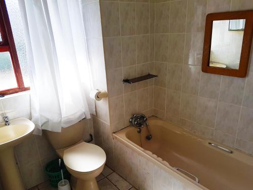 a bathroom with a toilet and a tub and a sink at Dumela Margate Flat No 31 in Margate