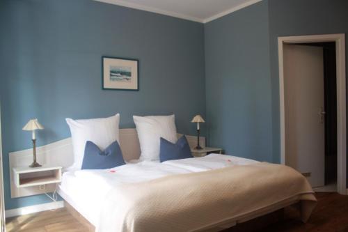 a blue bedroom with a large bed with blue walls at Hotel Haus Kranich in Prerow