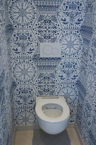 a toilet in a bathroom with blue and white tiles at De Bedstee Boutique Capsules in Amsterdam