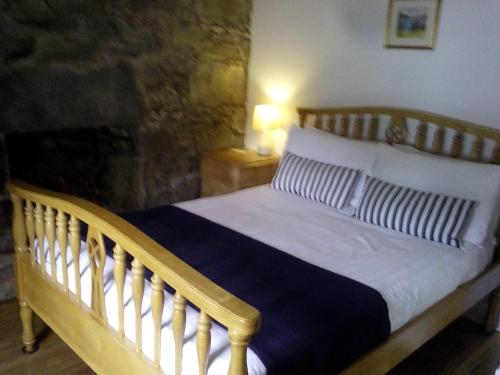 Cama de madera en un dormitorio con chimenea en Starfish Rooms, en Tarbert