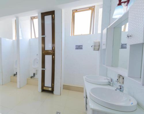 a white bathroom with a sink and a mirror at Tigers's apartment Hotel in Bujumbura