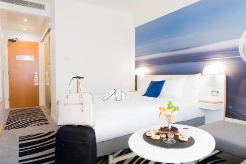 a hotel room with a white bed and a table at Novotel Firenze Nord Aeroporto in Sesto Fiorentino