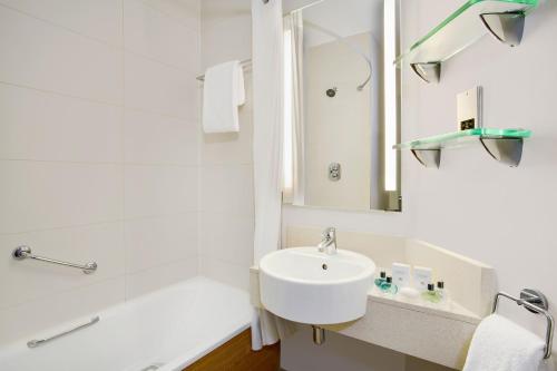 a bathroom with a sink, mirror, and bathtub at Jurys Inn Manchester City Centre in Manchester