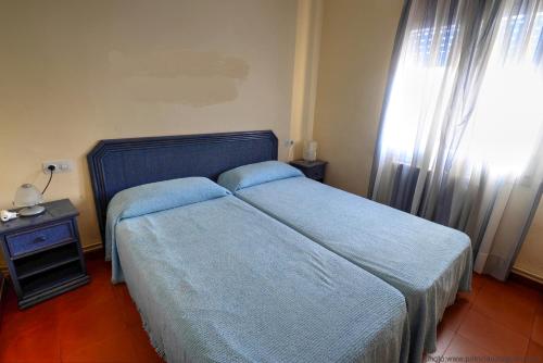 a bedroom with a bed with blue sheets and a window at Quintas de Sant Pol, a 50 metros de la playa de Sant Pol E29049 in Sant Feliu de Guíxols