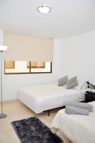 a white room with two beds and a mirror at Hotel Axis Inn By GEH Suites in Santa Marta
