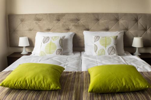 a large bed with two green pillows on it at City Rooms Szczecin in Szczecin