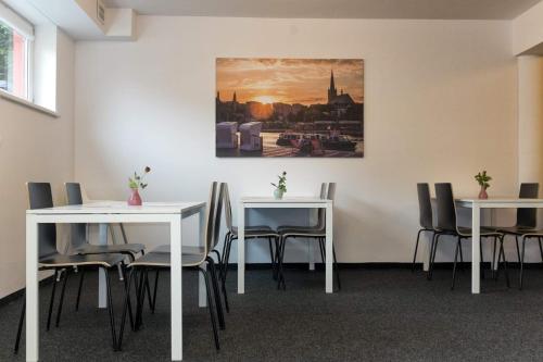 una habitación con mesas y sillas y un cuadro en la pared en City Rooms Szczecin, en Szczecin