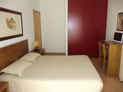 a bedroom with a bed and a desk with a laptop at Casa Lagar Da Alagoa in Manteigas