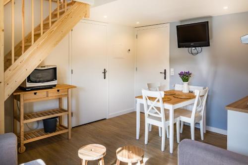 a living room with a dining room table and a staircase at Slapen aan de Bosweg in Zoutelande
