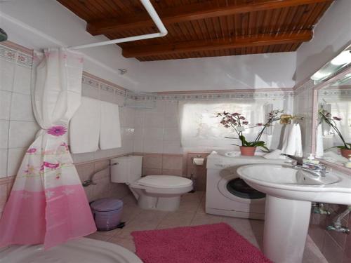 a bathroom with a toilet and a sink and a washing machine at Akadia Syros in Ermoupoli