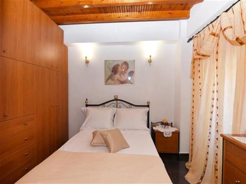 a bedroom with a bed with white sheets and wooden cabinets at Akadia Syros in Ermoupoli