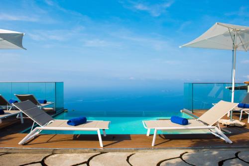 a group of chairs and umbrellas next to a pool at Villa Degli Dei Luxury House in Positano