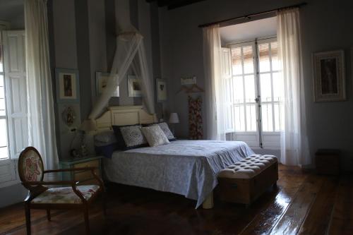 Un dormitorio con una cama y una silla y ventanas. en Alojamiento San Juan Bautista, en Cazorla